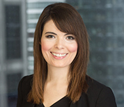 Melody Sousa sits in front of a large window with buildings blurred in the background. She is wearing a blouse.