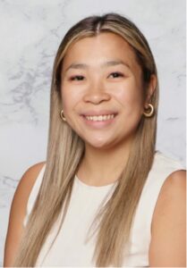 Kimberley seated in front of a light gray background wearing a white shirt.