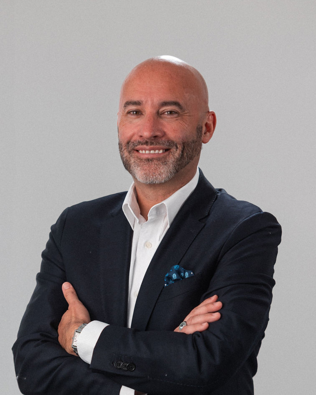 Jason Walker, a psychologist with a bald head and beard, stands with arms crossed in a dark suit and white shirt, smiling confidently against a plain background.