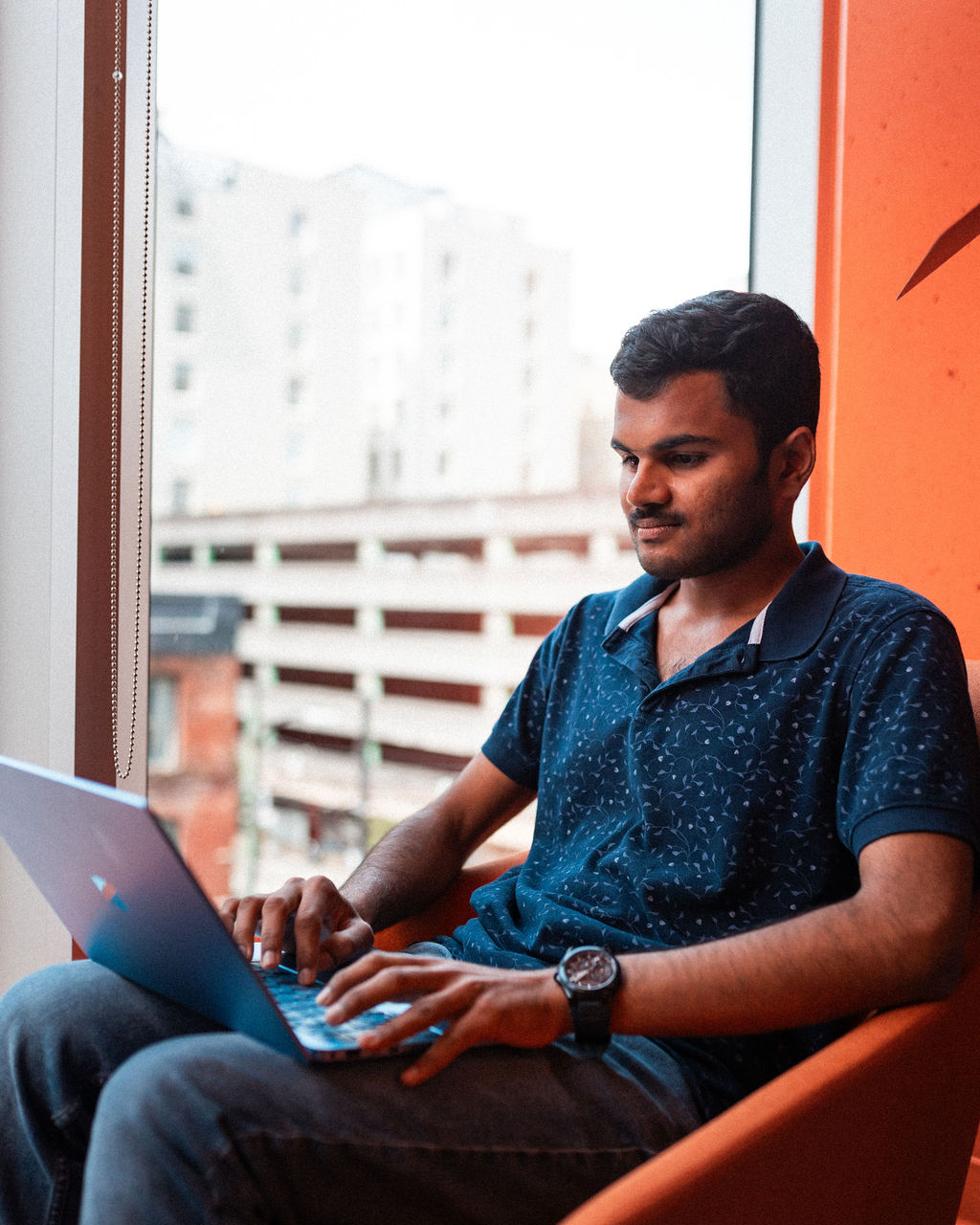 Student sits in chair working on laptop