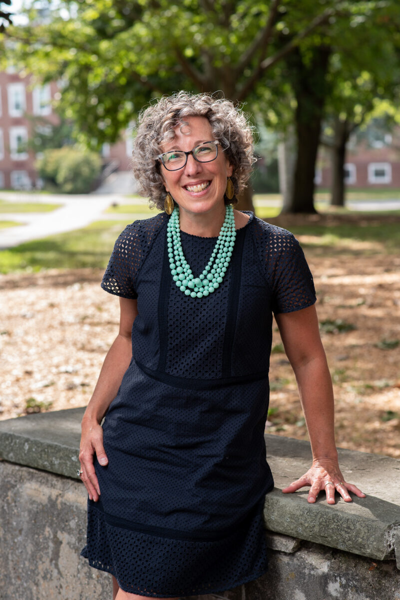 New vice president of academic affairs, Jeannie Uzzi is standing in doctoral regalia holding several papers in her hands ahead of a graduation ceremony.