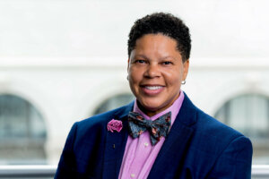 Maléka Ingram in a navy blue blazer, pink buttondown and blue bowtie.