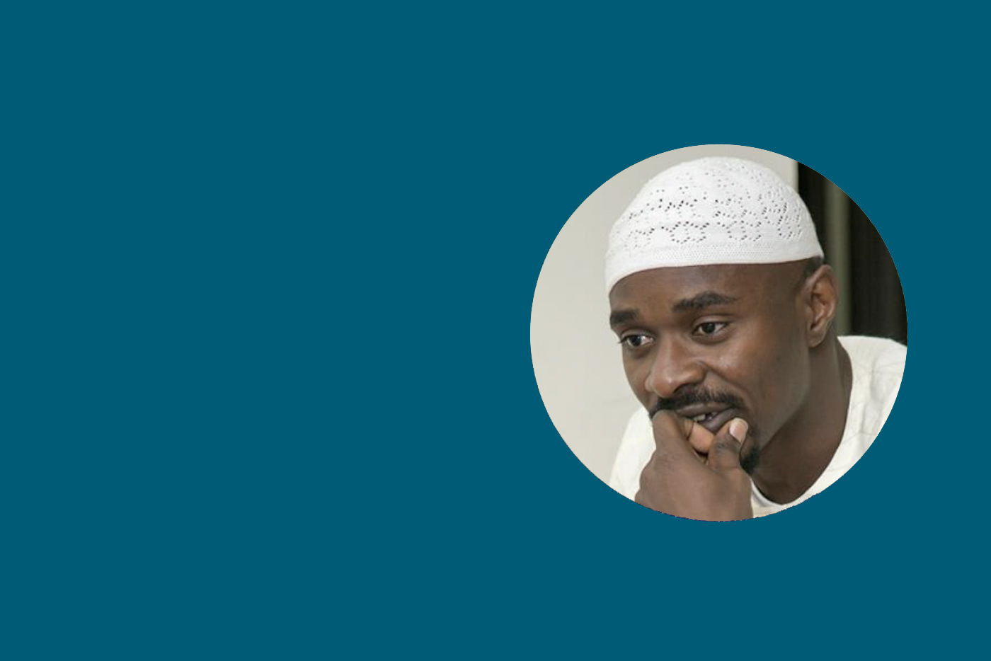Moshood Olanrewaju, Psy.D. faculty member and SCRA president, wears a white cap and clothing as he rests his chin on his hand, appearing thoughtful against a teal background.