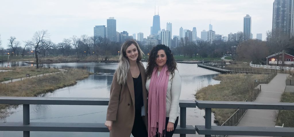 Two women stand on a bridge with a river and the Chicago skyline in the background on a cloudy day, highlighting opportunities for Vancouver students seeking internships in the city.