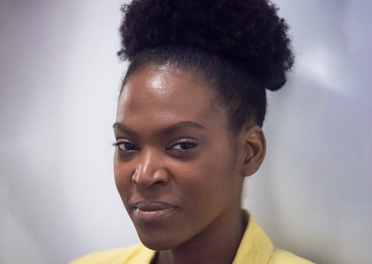 A closeup headshot of a Williams wearning a yellow shirt with collar and her hair up.