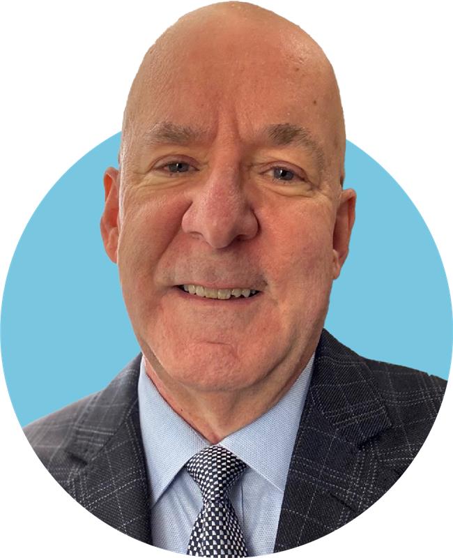 A middle-aged man in a suit and tie smiles at the camera with a light blue circular background, representing William J. Ehmann, provost at Adler University.