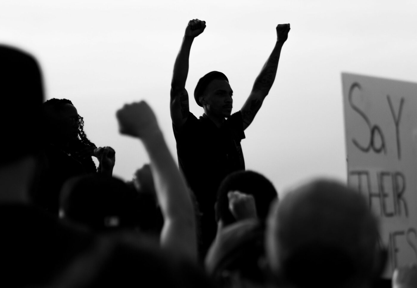 A group of people gather outdoors, some raising fists in the air, embodying the spirit to Break Through; a protest sign is partially visible on the right side of this Adler University 2020 Annual Report image.
