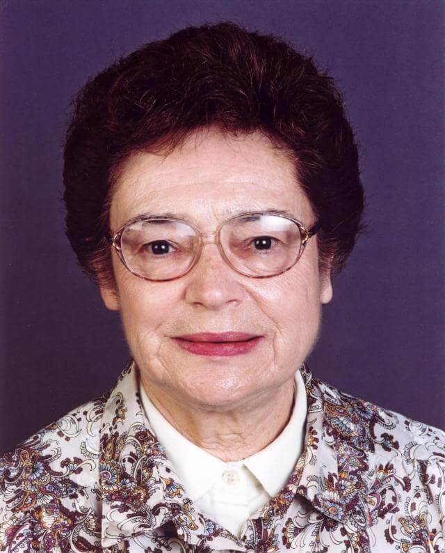 An older woman with short dark hair, glasses, and a patterned blouse is facing the camera against a plain, dark background—an image often seen in obituary tributes for notable figures like Eva Dreikurs Ferguson, Ph.D.
