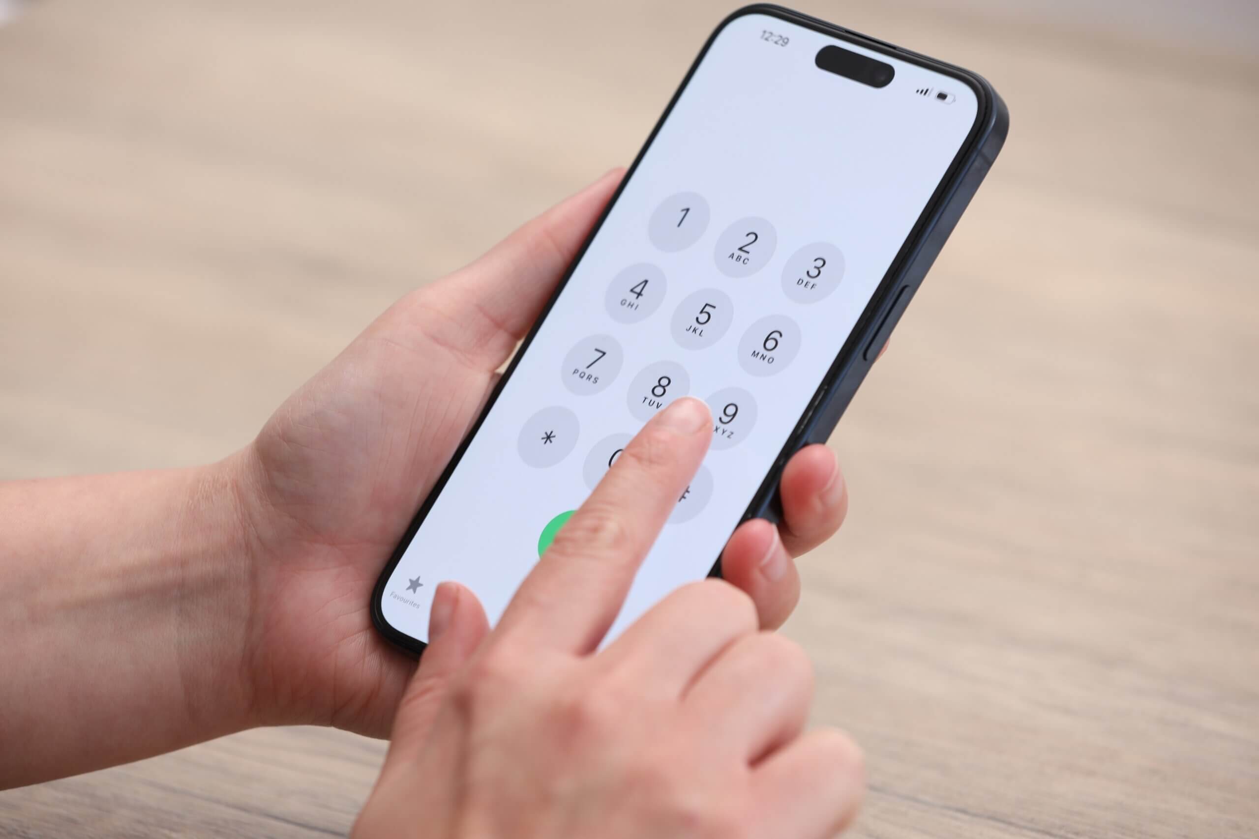 A person holds a smartphone and presses numbers on the keypad to make a call, possibly arranging details for relocating to Chicago.