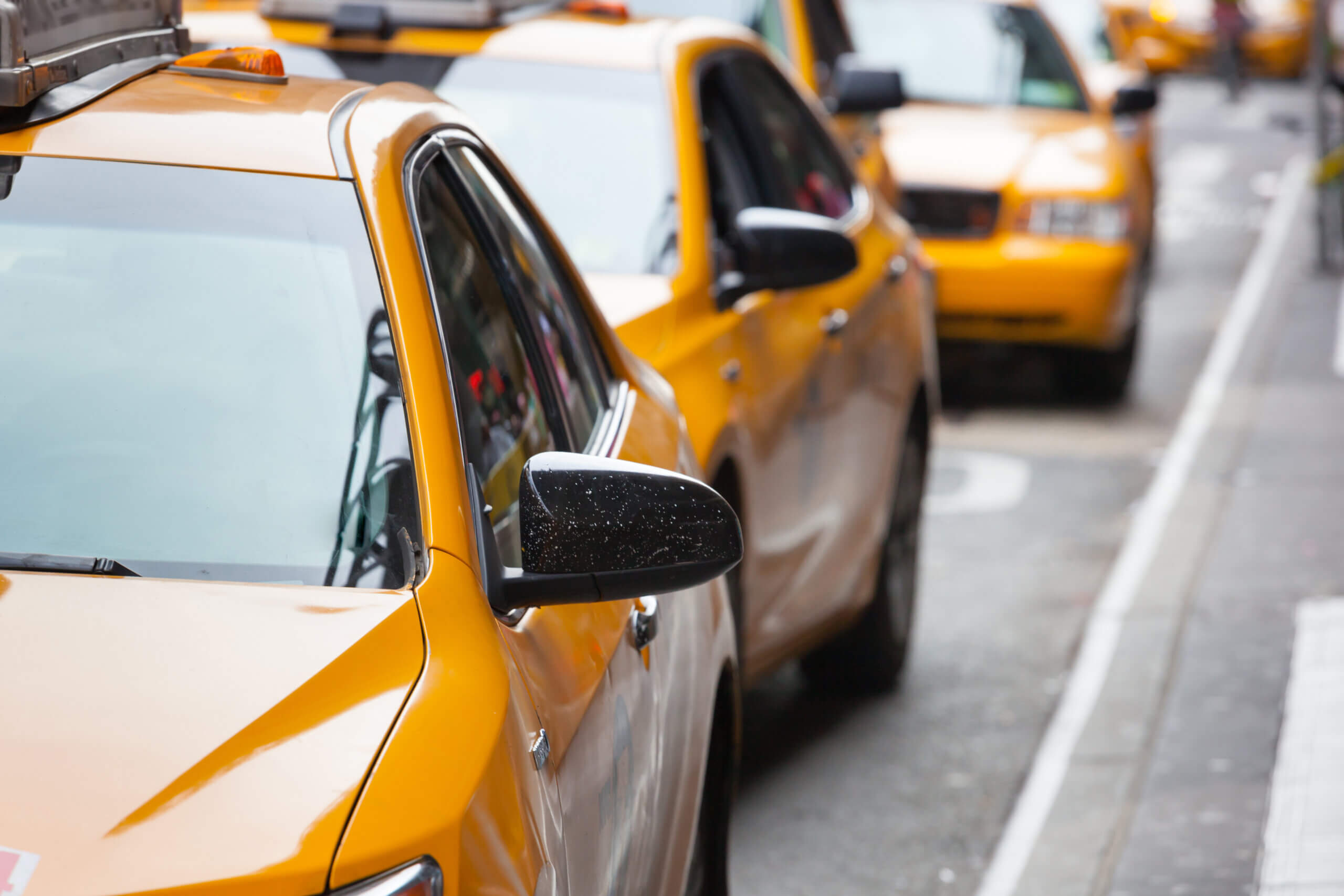 A row of yellow taxis is parked along the side of a city street, ready to help anyone relocating to Chicago start their new adventure.