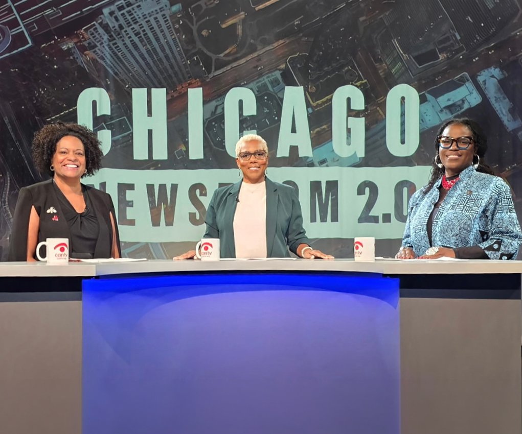 Three women, including President Coleman, sit behind a desk at a “Chicago Newsroom 2.0” studio for a discussion on women leaders in higher education.